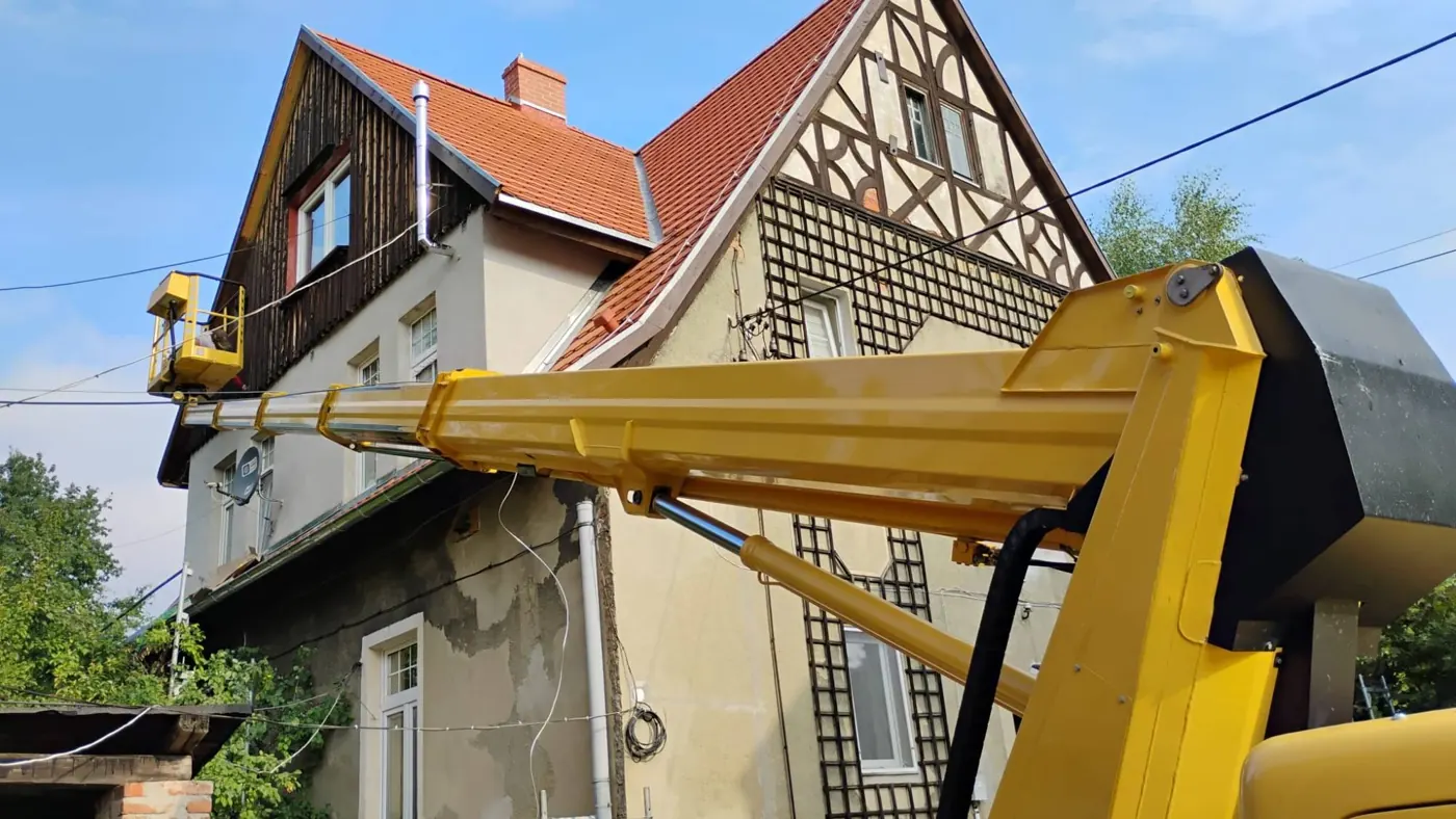 Podnośnik koszowy przy dachu starej kamienicy
